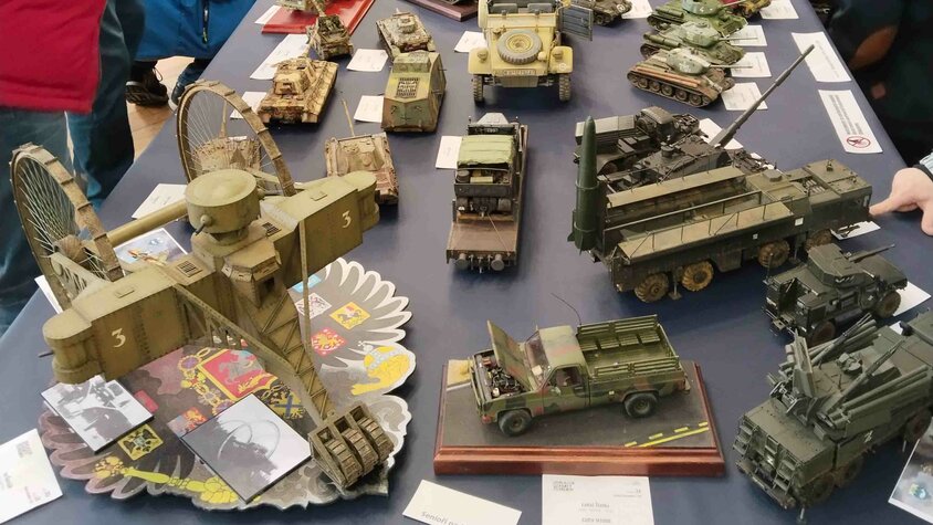 Besucher betrachten zahlreiche detailreiche Fahrzeugmodelle bei einer Modellbauausstellung.
