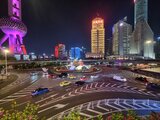 Nächtliche Straßenansicht im Finanzviertel von Shanghai mit beleuchteten Hochhäusern, der Oriental Pearl Tower im Hintergrund und dichtem Verkehr auf den Straßen – Momentaufnahme aus Jan Wengryns Zeit in China.