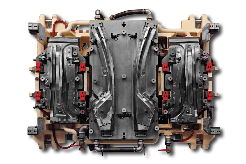 Eine Aufnahme aus der Vogelperspektive, die das Unterteil eines Warmumformwerkzeugs für die Vierfachfertigung von Strukturbauteilen zeigt. Dieses Werkzeug ermöglicht die simultane Produktion von je zwei A-Säulen und zwei B-Säulen. Die Aufnahme verdeutlicht die komplexe Gestaltung und hohe Kapazität des Werkzeugs, das für effiziente und präzise Produktionsprozesse in der Fahrzeugfertigung konzipiert ist