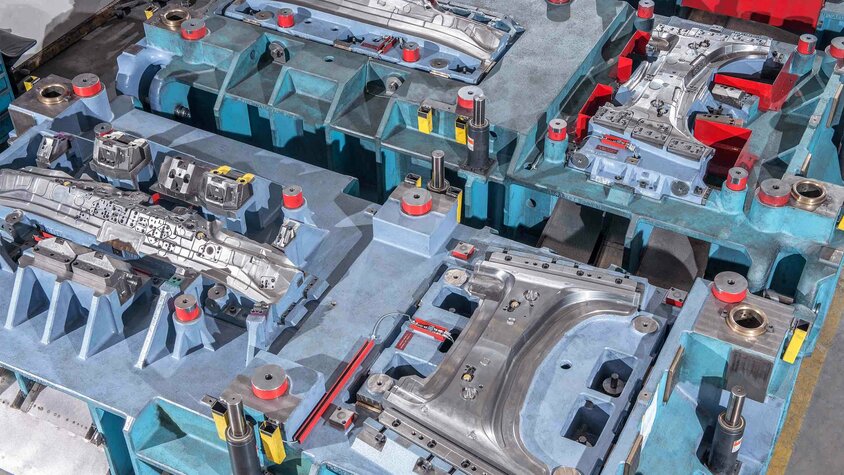 Linienwerkzeug für die Kaltumformung komplexer Bauteile Ausschnitt eines Linienwerkzeugs mit mehreren Umform- und Schneidstationen für die Kaltumformung von Karosserieteilen.