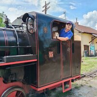 František Krumpolec stojí ve stanovišti historické parní lokomotivy a s úsměvem se dívá z okna.