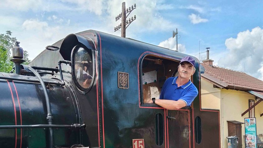 František Krumpolec steht im Führerhaus einer historischen Dampflokomotive und blickt lächelnd aus dem Fenster.