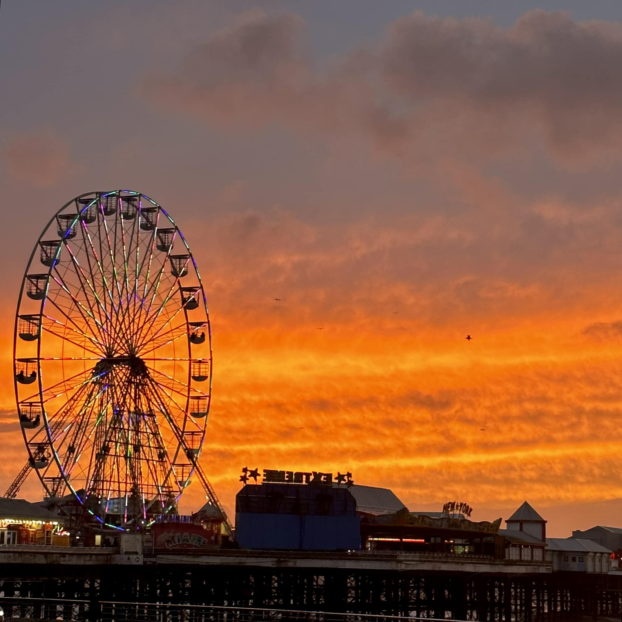 Ferris wheel in an amusement park at sunset in Blackpool with a glowing sky